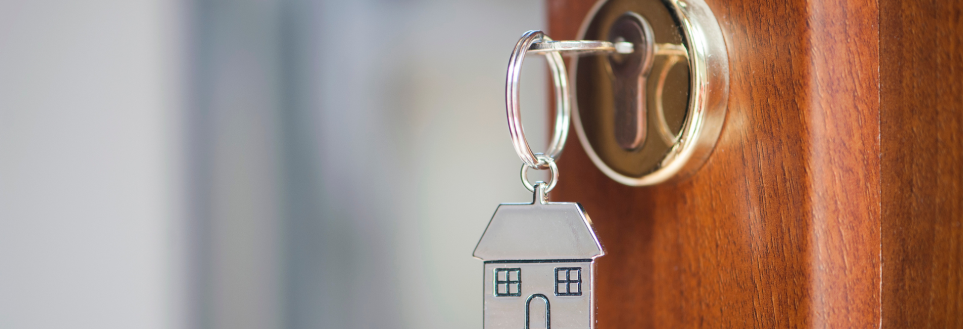 Open door with key in lock on a keychain of a house