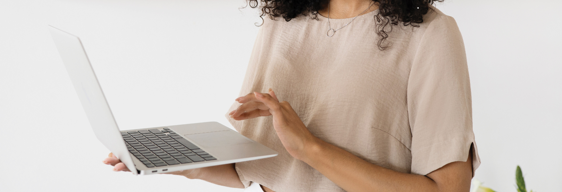 Woman in neutral colors smiling at her laptop Online Services Header