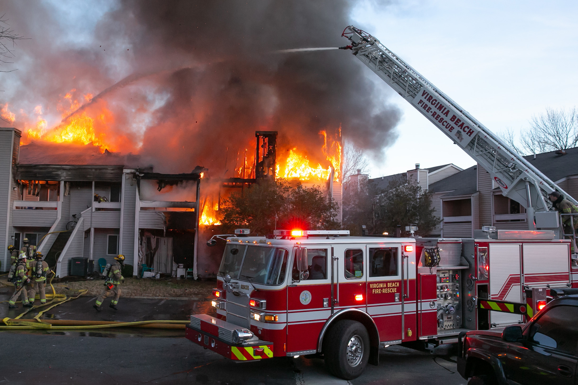 Fire truck with ladder extended putting out fire at apartment building