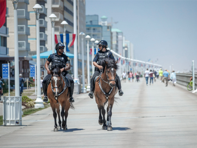 Two mounted patrol officers riding horses down boardwalk