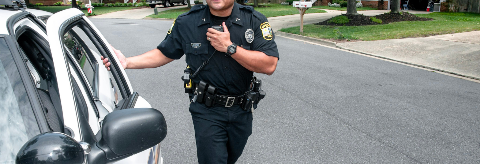 Police officer walking around police car in neighborhood