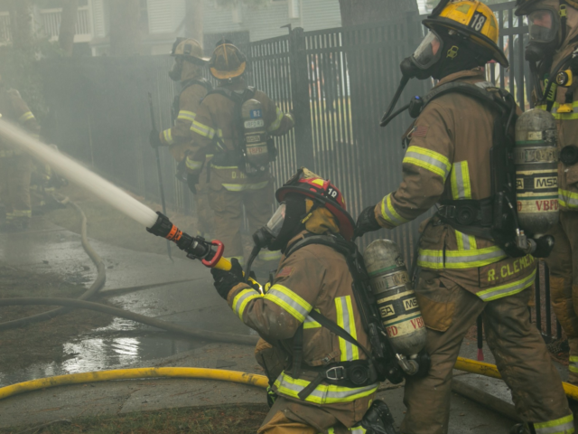 Firefighters with hose on ground