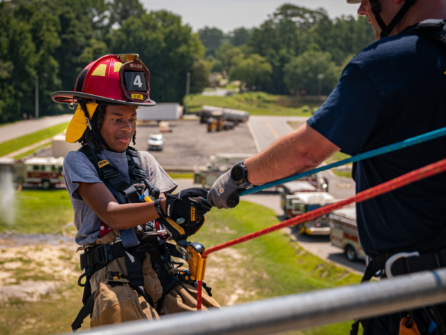 Fire cadet climbing over wall with ropes